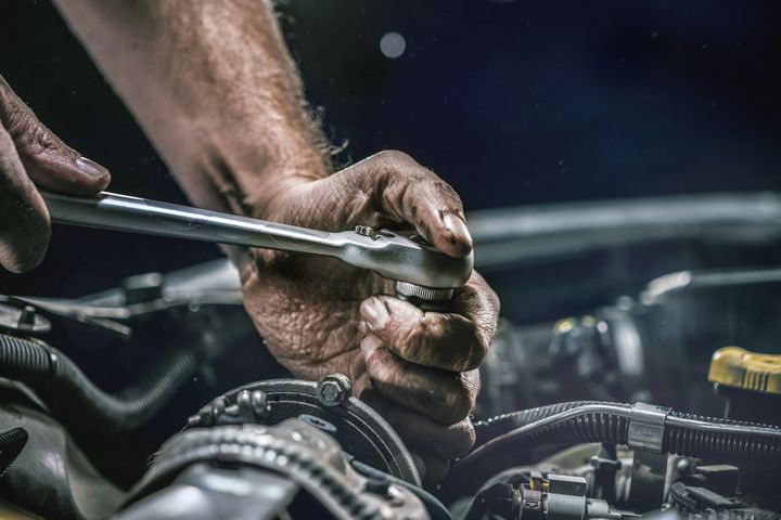 Auto mechanic working on car engine in mechanics garage Repair service authentic close-up shot