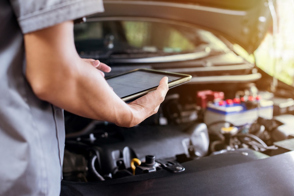 The mechanic uses a tablet to check the engine