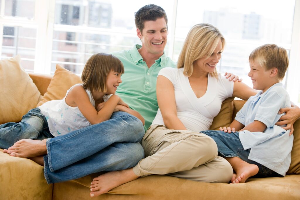 Fmaily sitting in living room together smiling